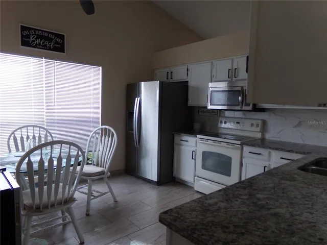 a kitchen with stainless steel appliances granite countertop a stove a refrigerator a sink a table and chairs