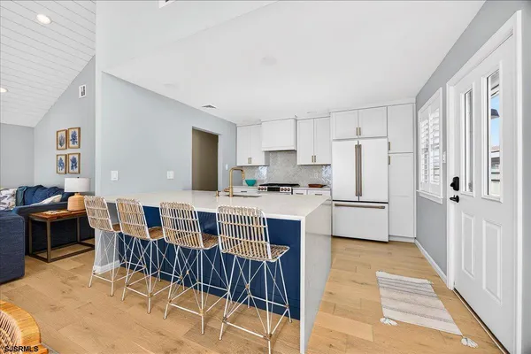 a kitchen with stainless steel appliances kitchen island granite countertop a dining table chairs and a refrigerator