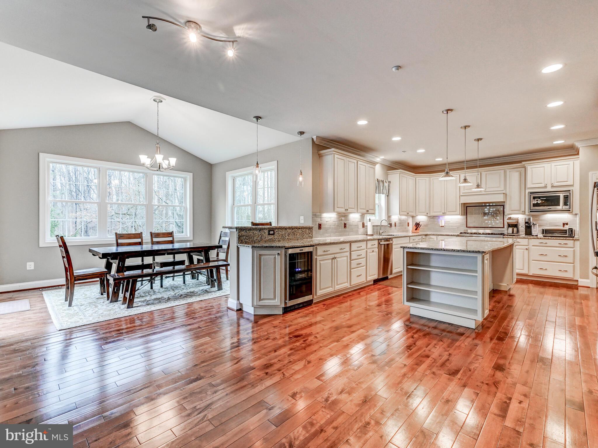 11707 Manor Road Glen Arm, MD 21057 - Photo 8 of 43 a kitchen with stainless steel appliances kitchen island granite countertop a stove top oven a sink dishwasher a dining table and chairs with wooden floor