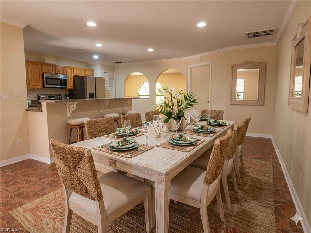 18414 Tulip Road Fort Myers, FL 33967 - Photo 11 of 37 Dining area featuring a wood-finish dining table and tile flooring, with an arched opening to an additional room