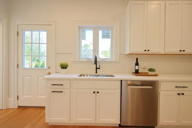 a kitchen with white cabinets and sink