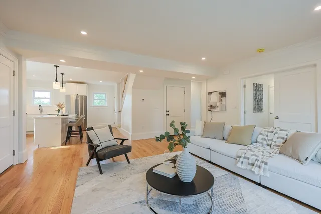 a living room with furniture and a dining table with wooden floor