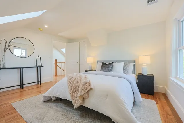 a spacious bedroom with a bed a dresser and wooden floor