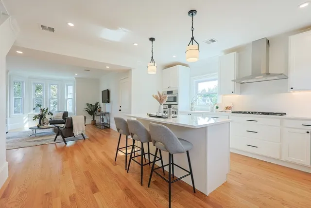 a kitchen with stainless steel appliances a dining table chairs stove and white cabinets