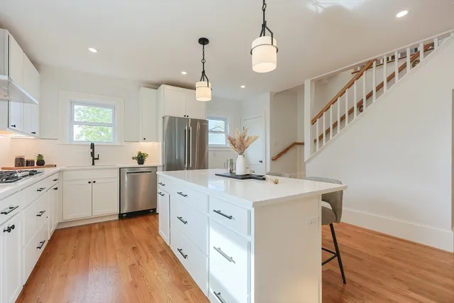 a kitchen with white cabinets appliances and wooden floor