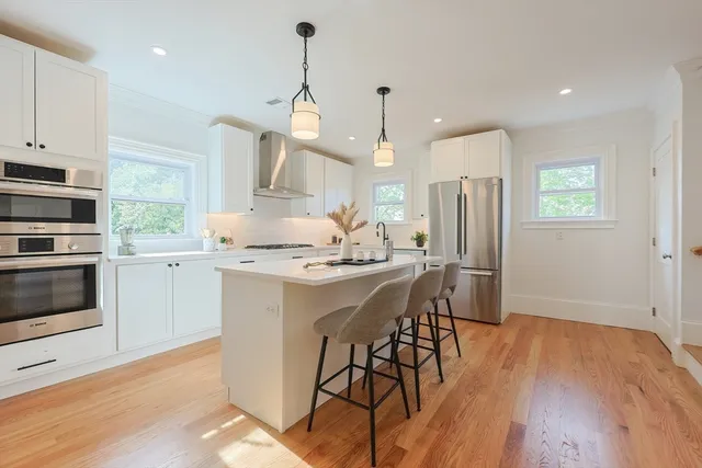 a kitchen with stainless steel appliances kitchen island granite countertop a stove a sink a refrigerator and a wooden floor