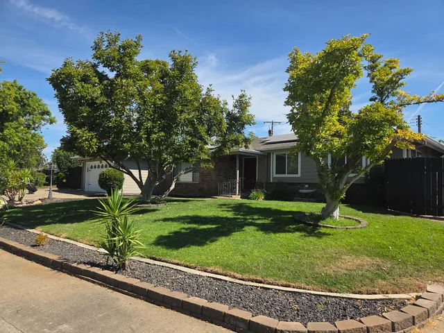 a garden with a bench in front of the house
