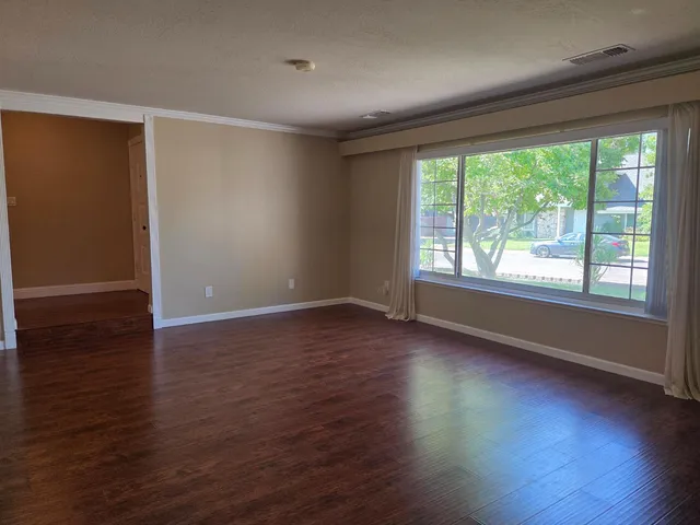 a view of an empty room with window and wooden floor