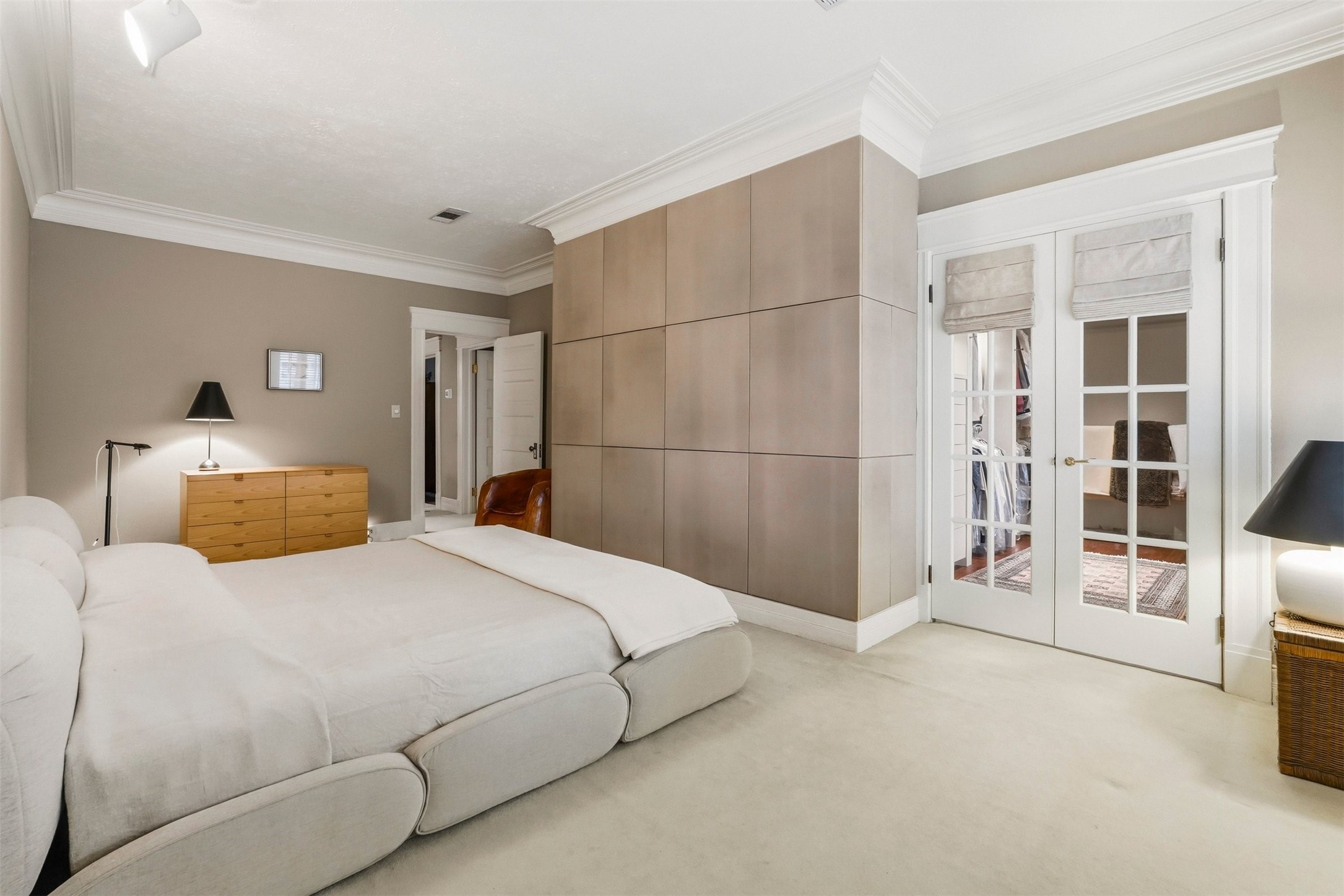 110 Stratford Street Houston, TX 77006 - Photo 19 of 40 This spacious bedroom features a modern design with neutral tones, a plush bed, and ample natural light from glass-paneled doors. It includes a stylish dresser and a cozy reading chair, creating a comfortable and inviting retreat.