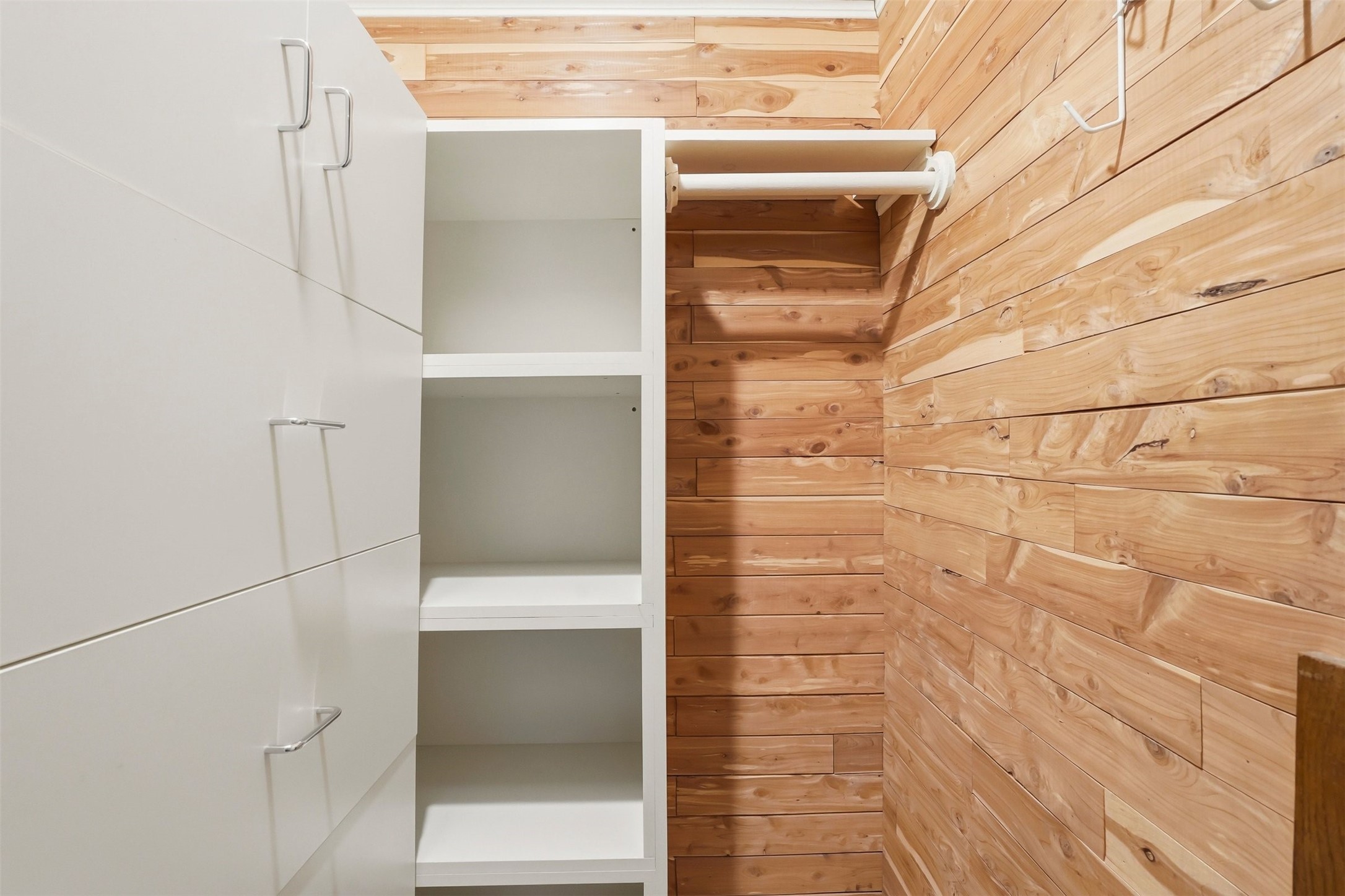 110 Stratford Street Houston, TX 77006 - Photo 24 of 40 This photo shows a compact walk-in closet with wooden walls and white shelving units, providing ample storage space.