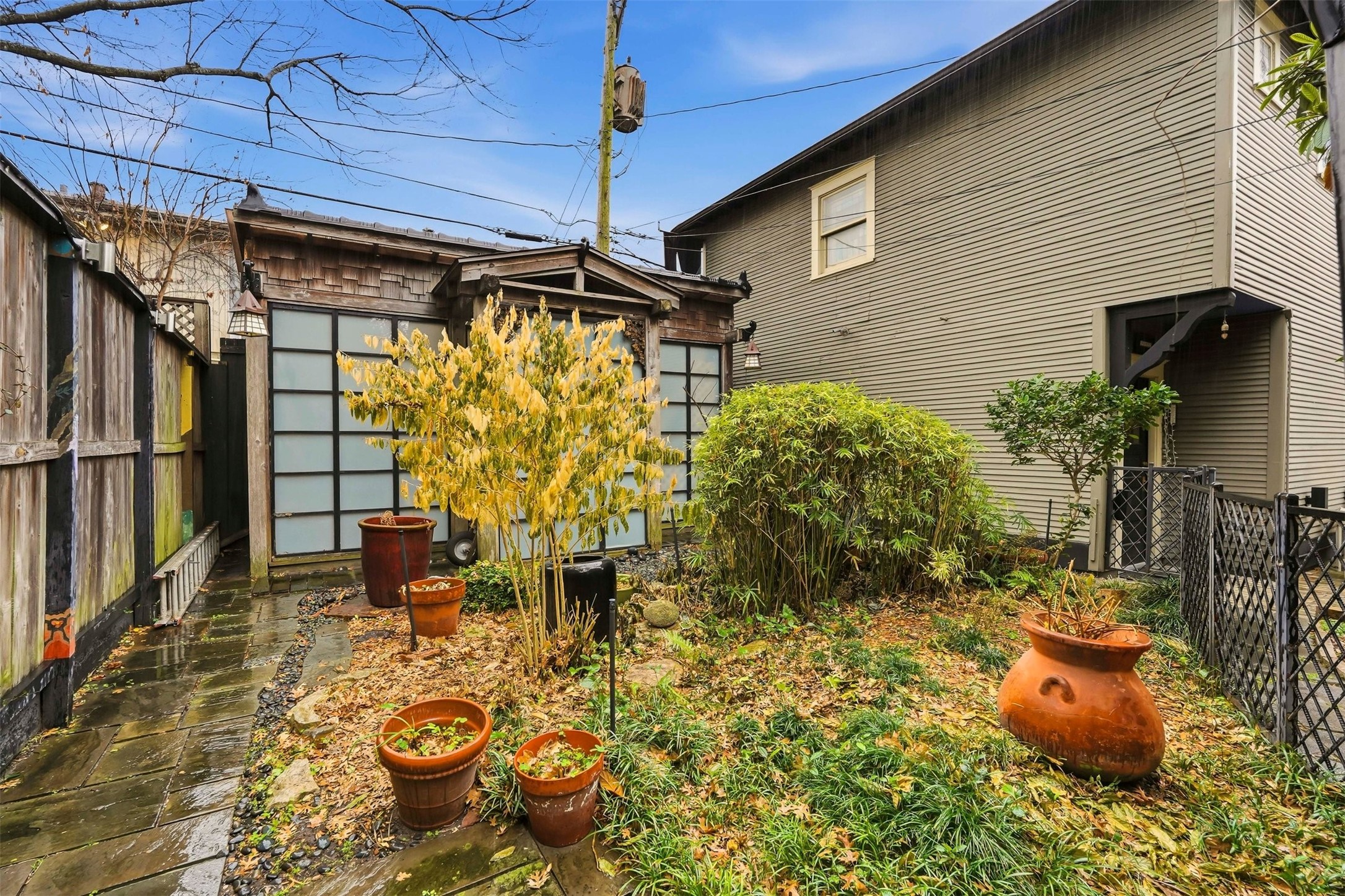 110 Stratford Street Houston, TX 77006 - Photo 29 of 40 Charming backyard with mature greenery, potted plants, and a rustic feel. The space is enclosed by a wooden fence and features a quaint garden shed, perfect for gardening enthusiasts.
