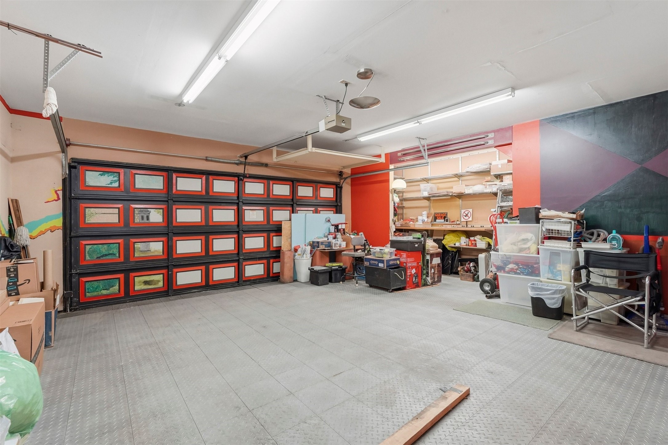 110 Stratford Street Houston, TX 77006 - Photo 35 of 40 Spacious garage with colorful, artistic garage doors and ample lighting. Features include organized shelving, workbench, and storage space, ideal for projects or additional storage.