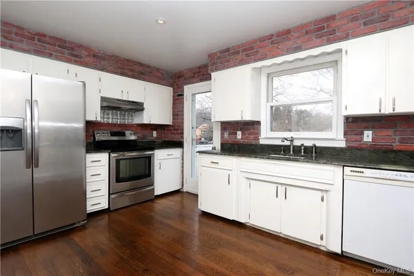 a kitchen with stainless steel appliances a sink cabinets and a window