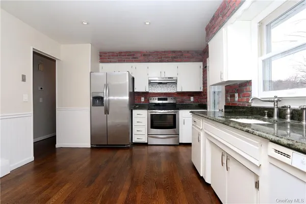 a kitchen with stainless steel appliances a stove a refrigerator a sink a microwave oven with wooden floor and cabinets