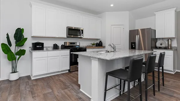 a kitchen with stainless steel appliances a sink a stove a table and chairs