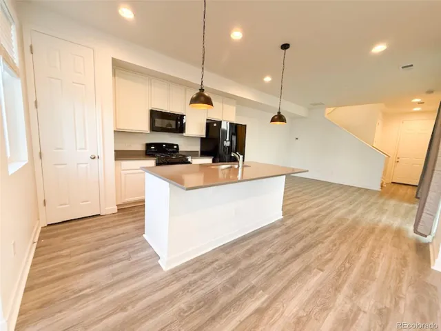 a large kitchen with stainless steel appliances kitchen island a large counter top and a wooden floor