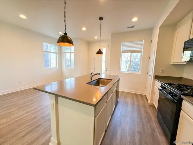 a kitchen with a stove a sink a window and wooden floor