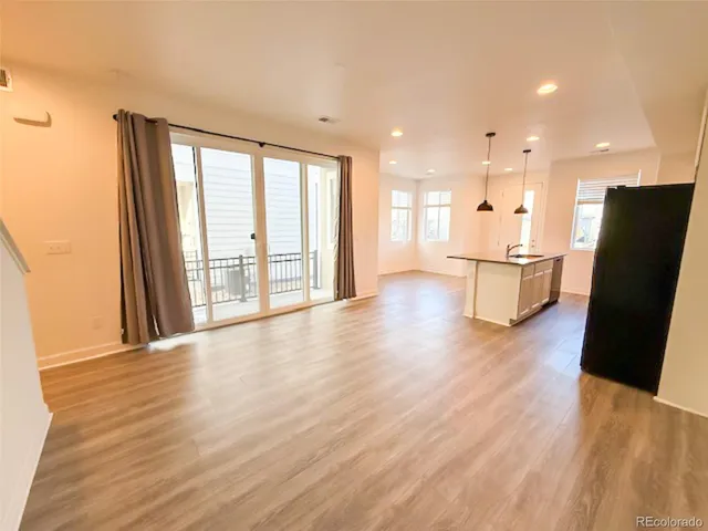 a view of a kitchen with refrigerator and wooden floor