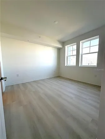 an empty room with wooden floor and windows
