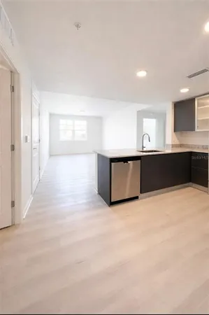 a view of a big room with wooden floor and kitchen