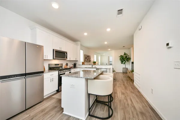 a kitchen with stainless steel appliances a refrigerator a stove a sink dishwasher and a microwave with wooden floor
