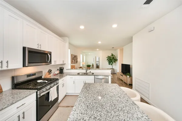 a large white kitchen with a stove a sink and a microwave