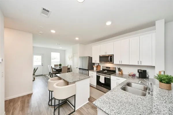 a kitchen with granite countertop a stove a sink a dining table and chairs