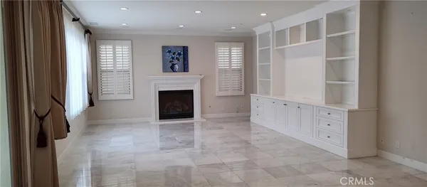 a view of an empty room with chandelier fan and fire place