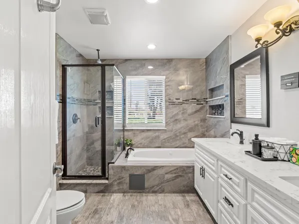 a bathroom with a granite countertop sink a toilet a mirror and shower