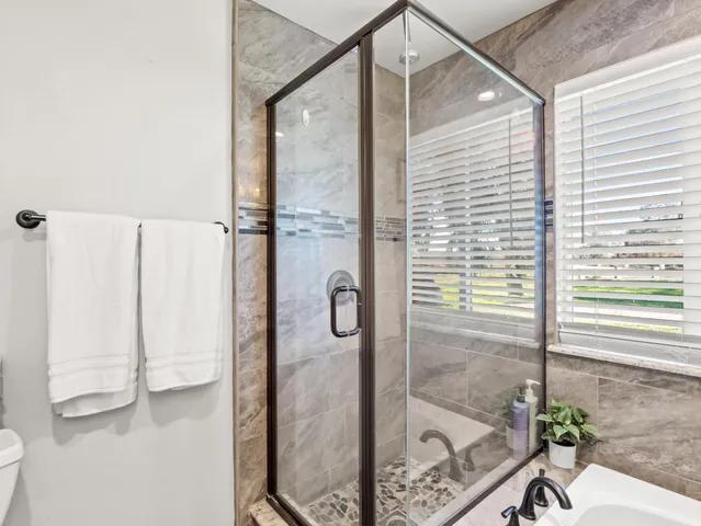a bathroom with a glass shower door and a window
