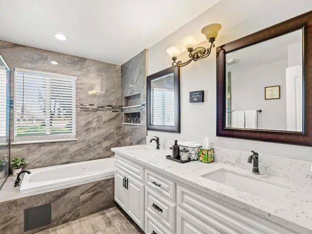 a bathroom with a granite countertop sink mirror and a bathtub