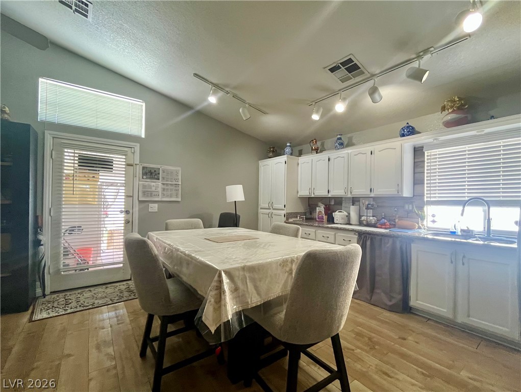 Gleaming wood-look floors complement the light-filled kitchen and dining area under vaulted ceilings.