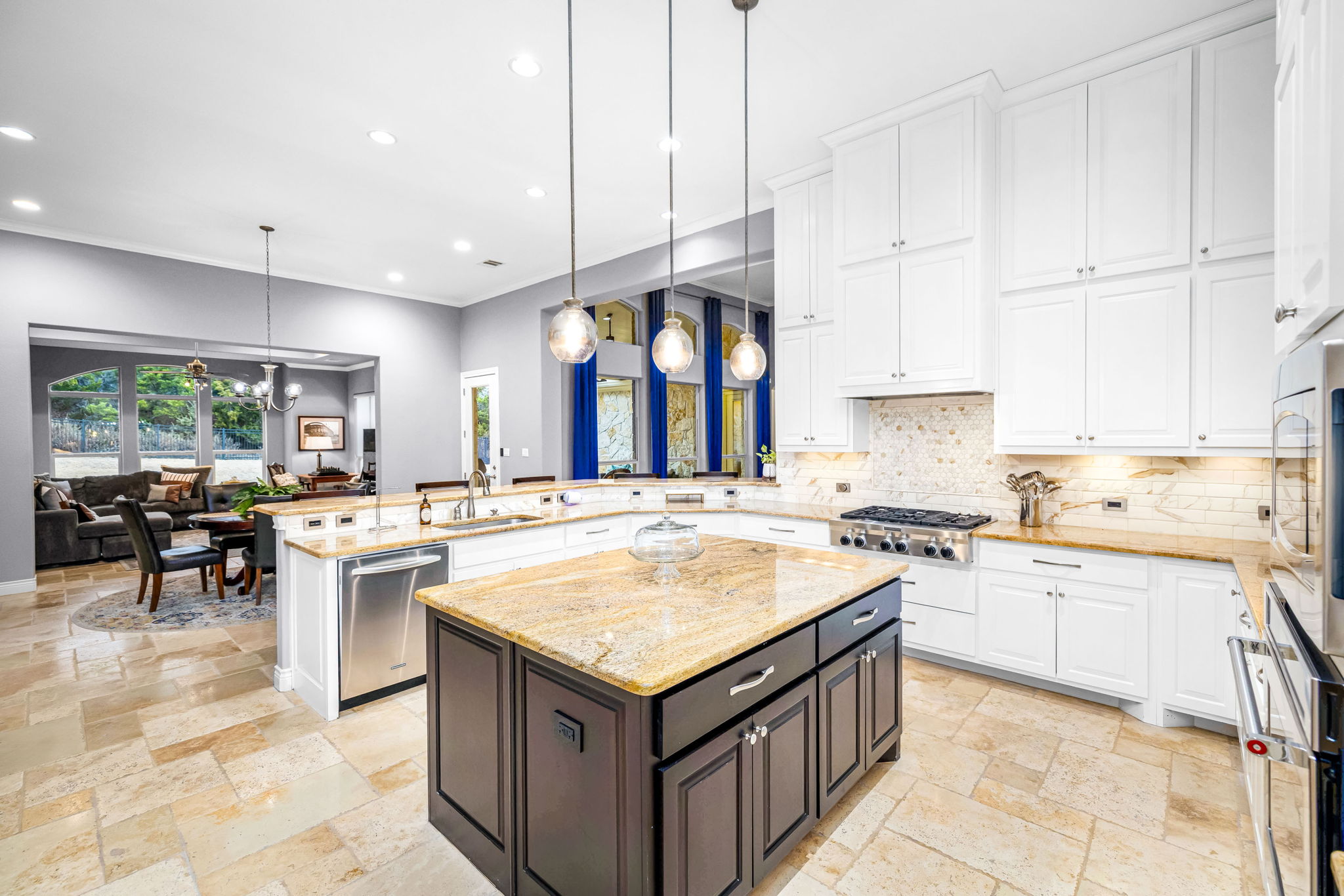 11604 Shoreview Overlook Austin, TX 78732 - Photo 25 of 40 Kitchen featuring light stone countertops, a center island, stainless steel appliances, tasteful backsplash, and stone tile flooring