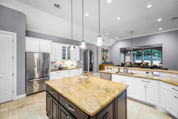 a kitchen with stainless steel appliances kitchen island granite countertop a refrigerator a sink dishwasher a stove and a refrigerator