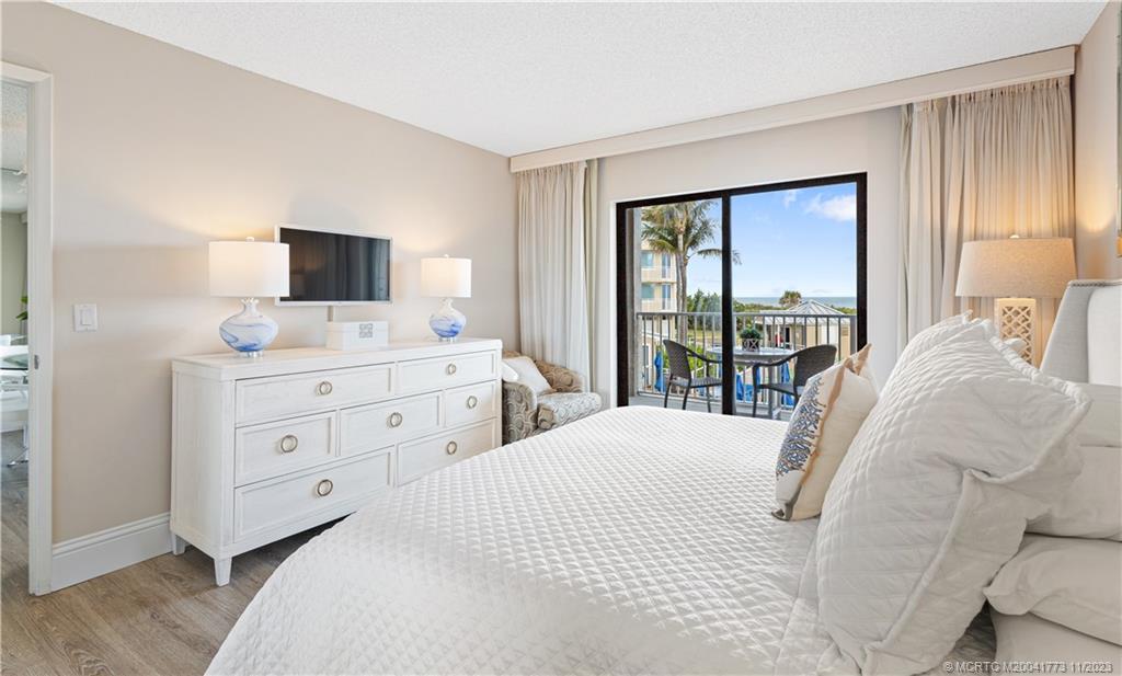 429 Northeast Tradewind Lane, Unit 2109 Stuart, FL 34996 - Photo 20 of 35 a bedroom with a bed and a flat tv screen on the dresser