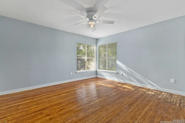 a view of an empty room with wooden floor and a window