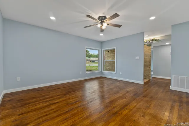 a view of an empty room with wooden floor and a window