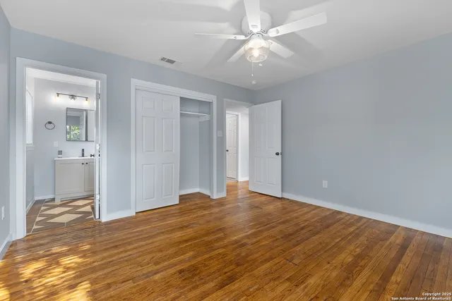 an empty room with wooden floor and fan