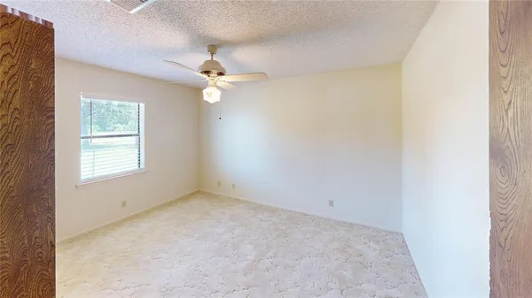 an empty room with a window and a fan