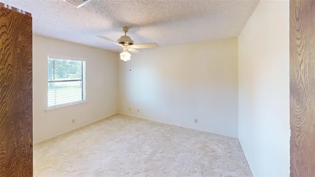 an empty room with a window and a fan
