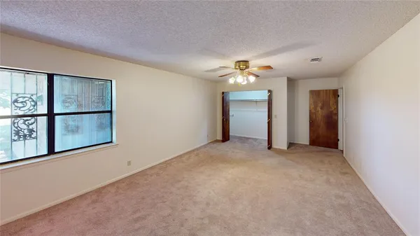 an empty room with chandelier fan and windows