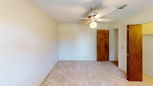 an empty room with closet and a chandelier fan