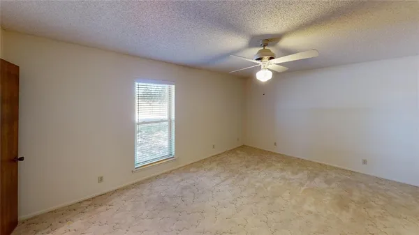 an empty room with windows and ceiling fan