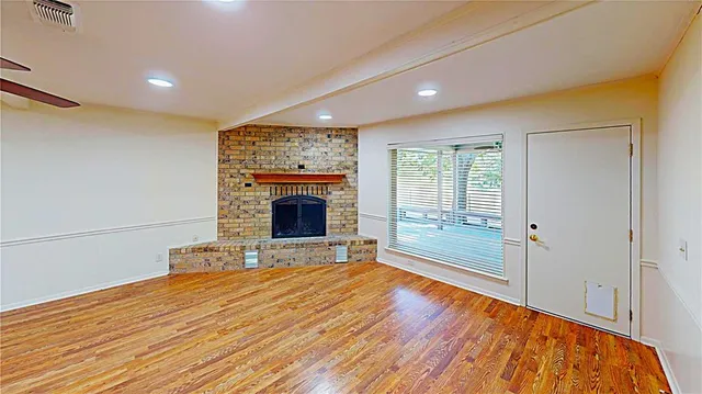 a view of empty room with wooden floor and fireplace