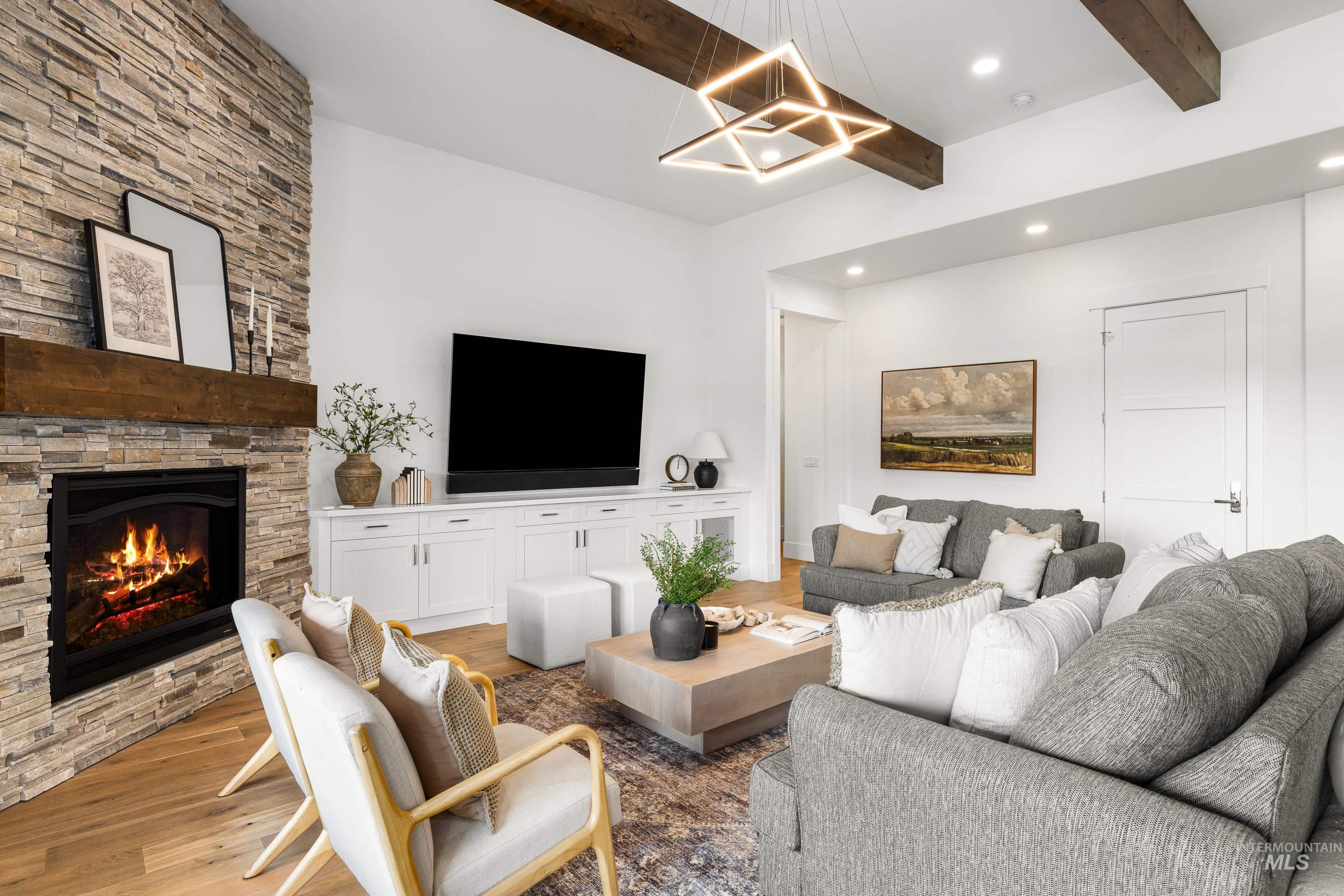 2379 South Mallard Wing Way Eagle, ID 83616 - Photo 8 of 48 Living room with beamed ceiling, wood finished floors, recessed lighting, a fireplace, and a chandelier