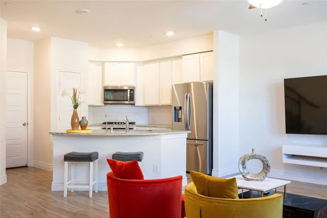 a kitchen with stainless steel appliances granite countertop a refrigerator a stove a sink and a microwave