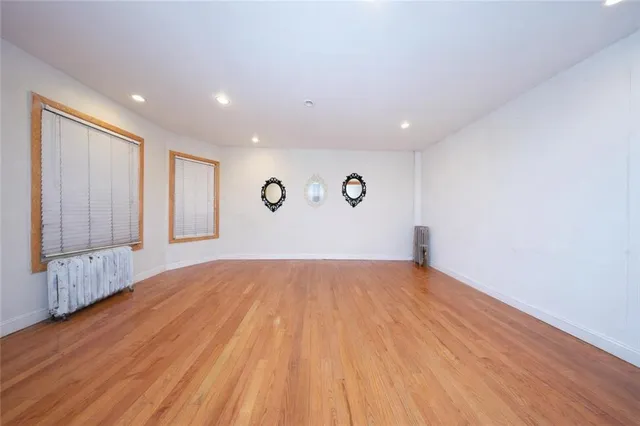 a view of an empty room with wooden floor and window