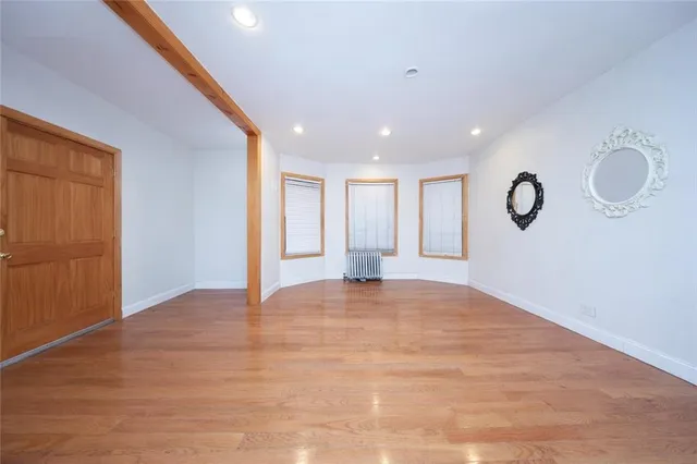 a view of an empty room with wooden floor and window