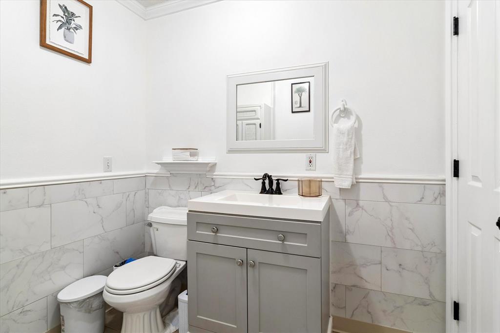 3007 McReynolds Road Sanger, TX 76266 - Photo 15 of 39 Bathroom featuring marble-look tile wainscoting, a light grey vanity with a white countertop, and a framed mirror