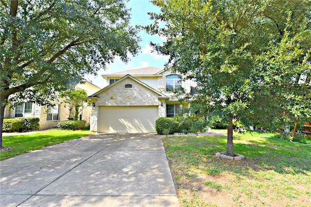a front view of a house with a yard and trees